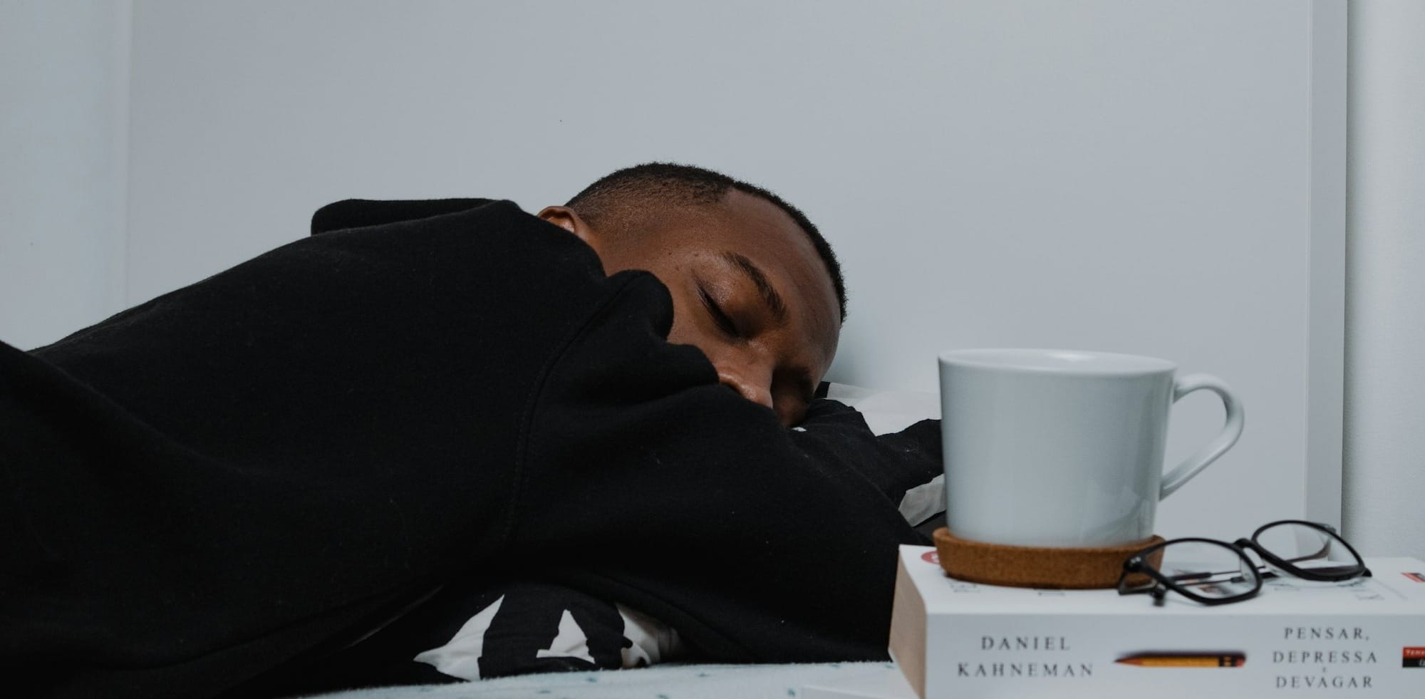 a man sleeping on a bed next to a stack of books